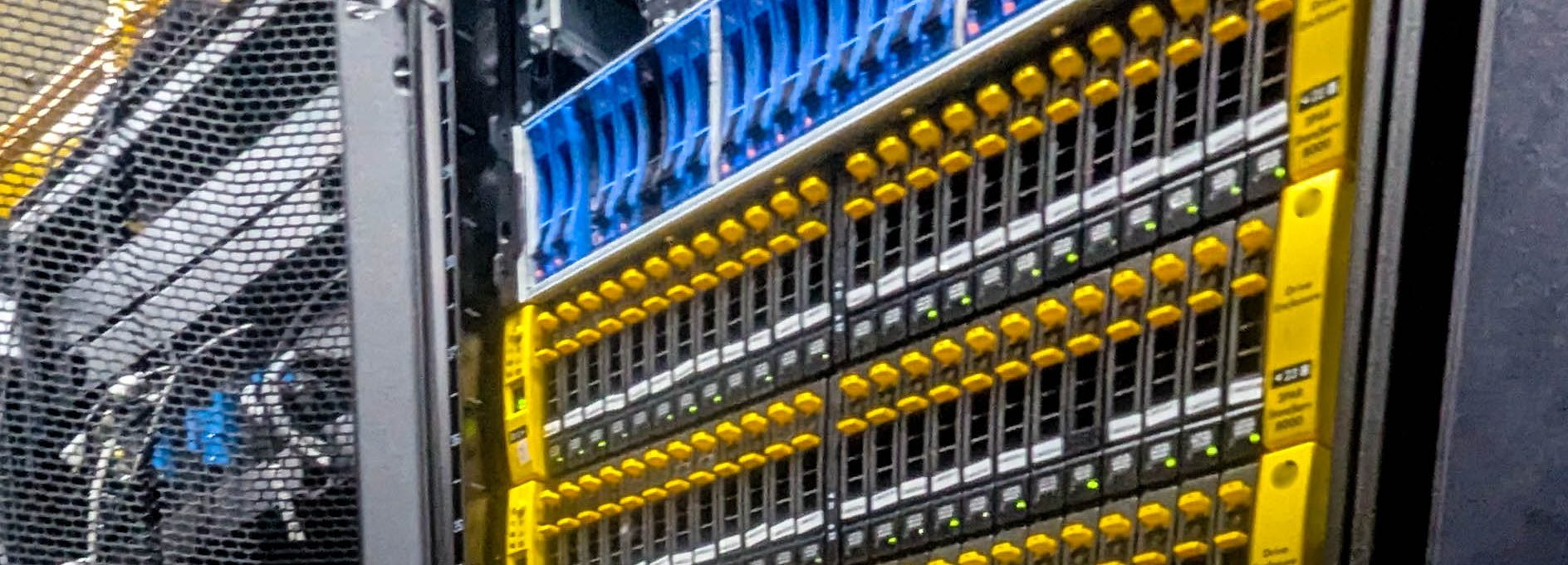 Close-up view of an HPE 3PAR StoreServ 8000 storage array mounted in a data center rack, featuring multiple rows of hard drive bays with distinctive yellow release latches and green status LEDs.